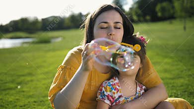 Mother blowing soap bubbles with special daughter