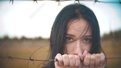 Girl brunette refugee behind barbed wire camp lifestyle slow motion video. the concept of freedom is upset Woman hands
