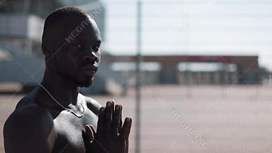 African American man praying to God on the street and looking into the camera. Concept of faith, religion, poverty