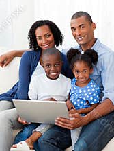 Afro-American family using a laptop on the sofa