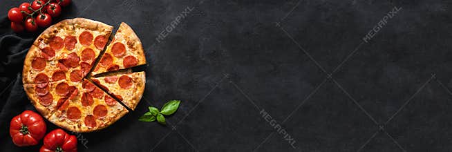 Tasty pepperoni pizza and cooking ingredients tomatoes, spices, basil on black concrete background