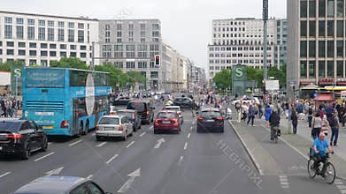 Many pedestrians go on crosswalk, cars waiting for green traffic light
