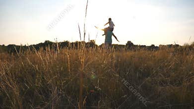Little boy sitting on shoulders of his daddy and playing raised hands as airplane. Happy father and son playing on the