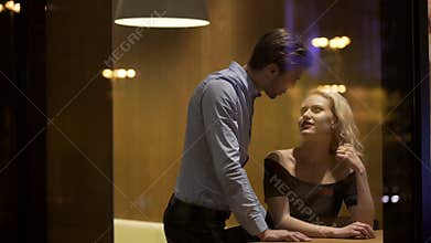 Man flirting with gorgeous blond woman at restaurant in the evening, pick -up