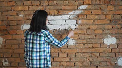 The woman paints a red brick in house in white color