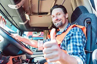 Truck driver sitting in cabin giving thumbs-up