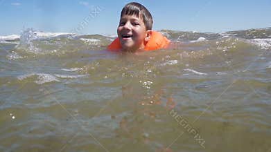 Boy in lifejacket swim in sea with waves