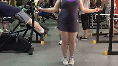 Overweight woman jumping rope in the gym, weight loss and fitness, slow-mo