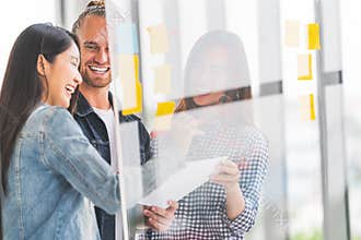 Multiethnic diverse group meeting write project plan on transparent glass board. Small business startup or teamwork concept