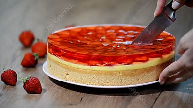 Cutting a piece of strawberry cake with jelly.
