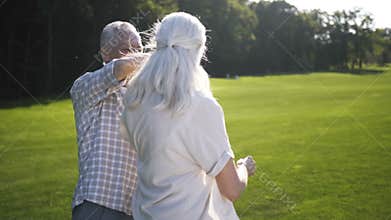 Happy senior aged couple dancing outdoors on lawn