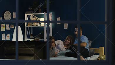 Relaxing family watching TV on bed together