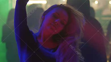 Pretty blonde woman smiling, dancing and enjoying atmosphere at nightclub party