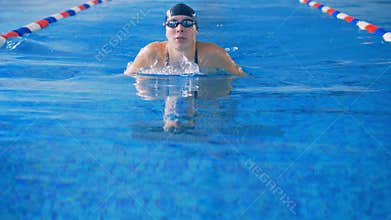 A female athlete swims the crawl style in a pool. 4K.