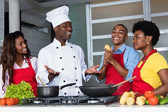 African american chef teaching women and men at kitchen