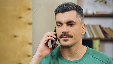 Gray-haired man talking on cellphone at home, making appointment with friends