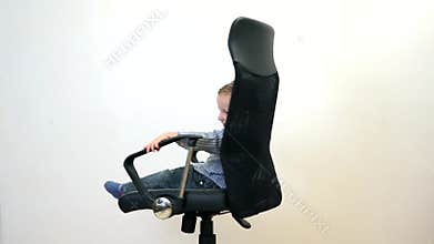Fuuny kid spinning in an office chair, manager has fun at work
