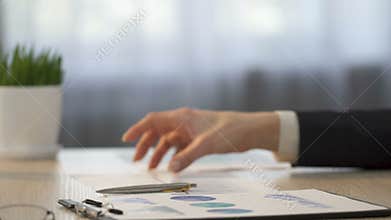 Financial analyst comparing company statistics and making notes on graphs