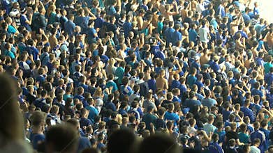 Group of football fans applauding and chanting at stadium in organized manner