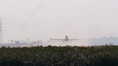 Crop duster spraying chemicals over a cotton field - slow motion