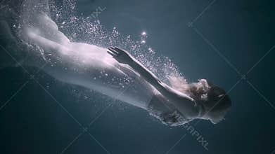 Beautiful woman swimming underwater in white elegant dress