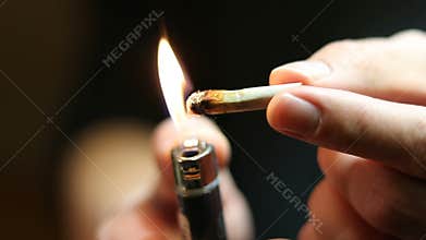 Man lighting marijuana joint roach