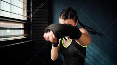 Beautiful young moving boxing woman training punching in fitness studio