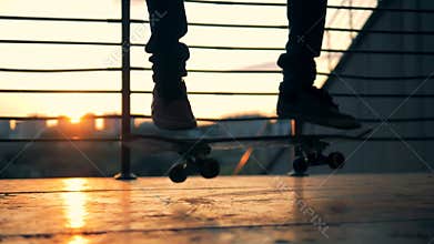 SLOW MOTION. Silhouetted skateboarder skateboarding and jumping on a sunset background.