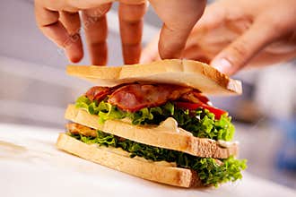 Chef making sandwich in rustic style with bacon and fresh vegetables