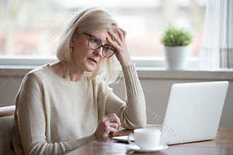 Confused mature woman thinking about online problem looking at l