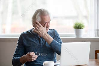 Fatigued mature man taking off glasses suffering from tired eyes