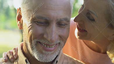 Old woman coming to man from behind, couple hugging and happily smiling, love
