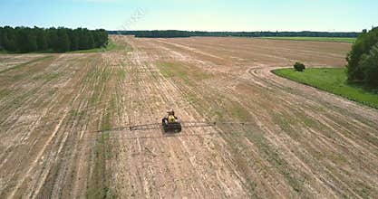Flycam follows fertilizer spreader driving along harvested field