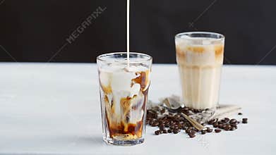 Concept of coffee and cocktails. Cream poured into coffee with ice