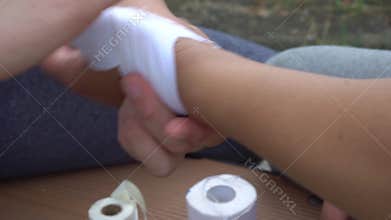 One human uses white plaster to cover part of another hand. It is injured. Human finished covering hand and started to