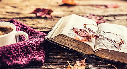 Cup of coffee old book glasses and autumn leaves.