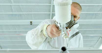 Mechanic painting car parts with electric spray gun in garage 4k