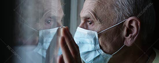 Older male hospital patient in face mask looking through window side view