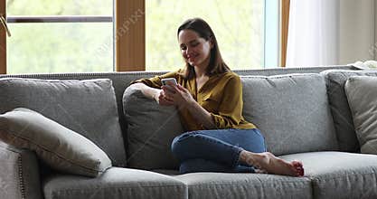 Young female sit on couch hold phone enjoy dating online