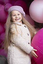 Kid birthday party concept. girl in beret playing with pink, purple balloons, outdoors. childrens emotions.