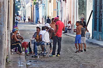 The authentic side of Cuba: Neighbors spontaneously make music with a bucket instead of a drum in the streets of Havana, Cuba