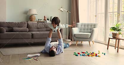 Dad lying on floor hold son on arms in air