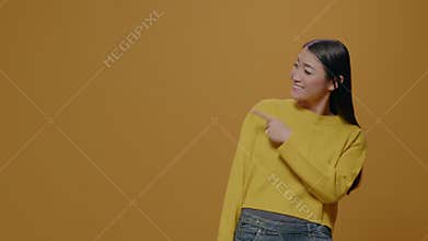 Positive adult pointing at left side of studio in front of camera