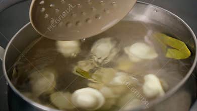 Cooking homemade dumplings or ravioli with meat. Culinary concept. Cook the dumplings in a saucepan, boil