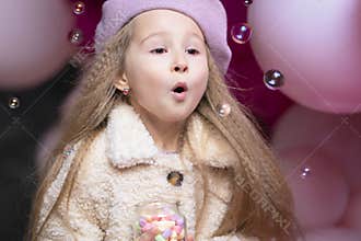 Girl in beret playing with pink, purple balloons, soap bubbles, marshmallow