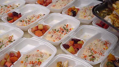 Volunteer packs free Christmas dinners in meal prep containers. Holiday basket of groceries. Charities, churches