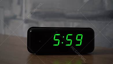 6 am at the digital alarm clock on the table in bedroom. Clock ringing and wakes up us early in the morning. It&#x27;s