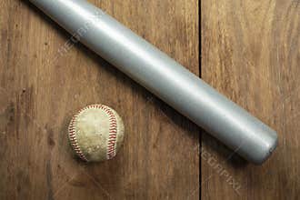 Baseball ball and baseball bat isolated on wooden background.