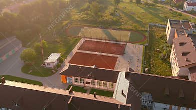 School with green lawn. Public school building. Exterior of the building with playground.