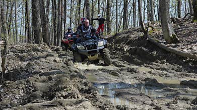 A group of ATVs rides through the mud in the spring forest. Extreme type of outdoor activities. Quad bike ride.